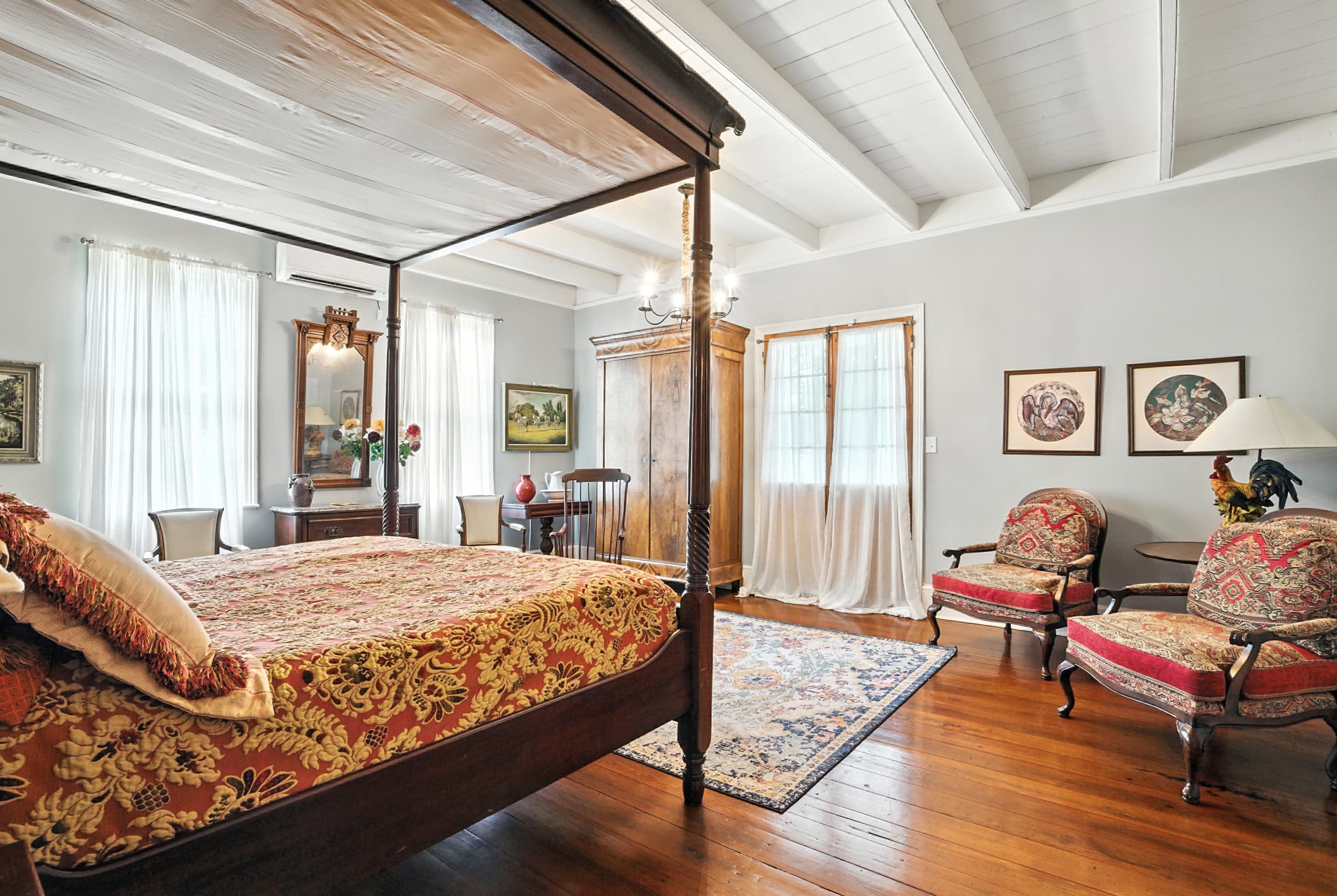 Elegant suite featuring a grand four-poster bed, original hardwood floors, exposed beams, and a cozy sitting area.