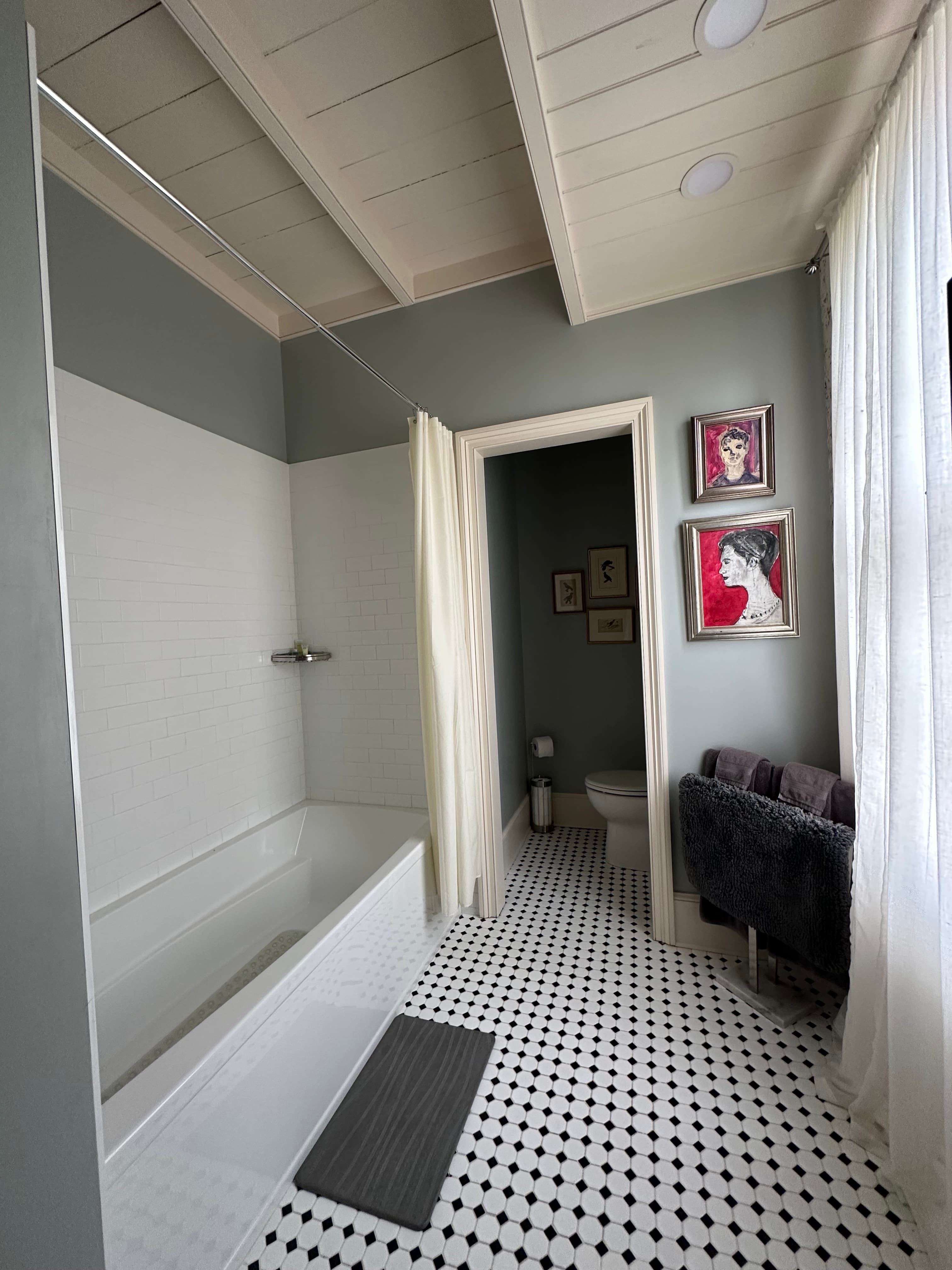 Enjoy this bright bathroom featuring a deep soaking tub, classic black and white tile floors, and elegant exposed ceiling beams.