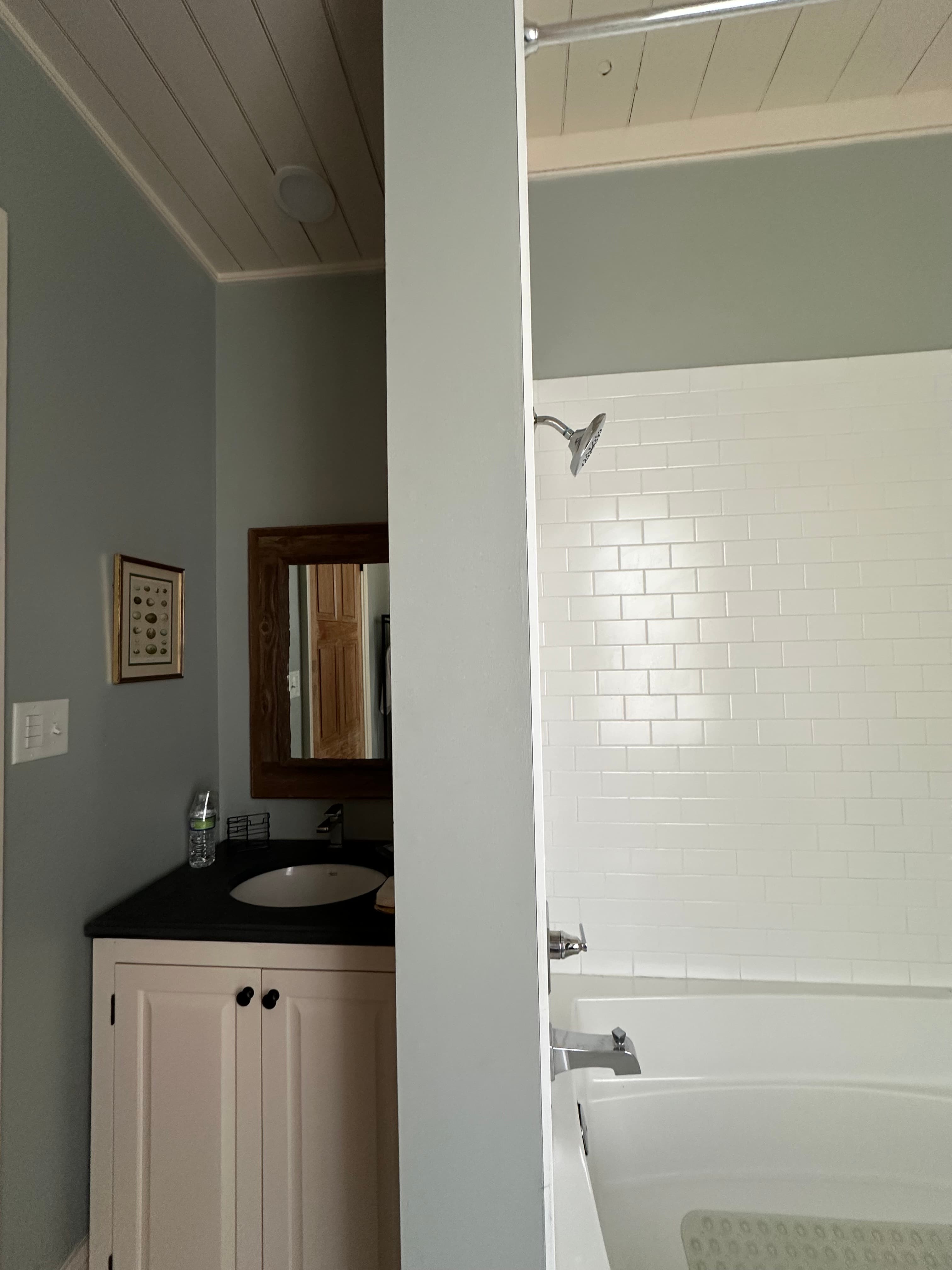 Clean bathroom featuring a vessel sink vanity, plank ceilings, and a classic white subway tile shower and tub combo.