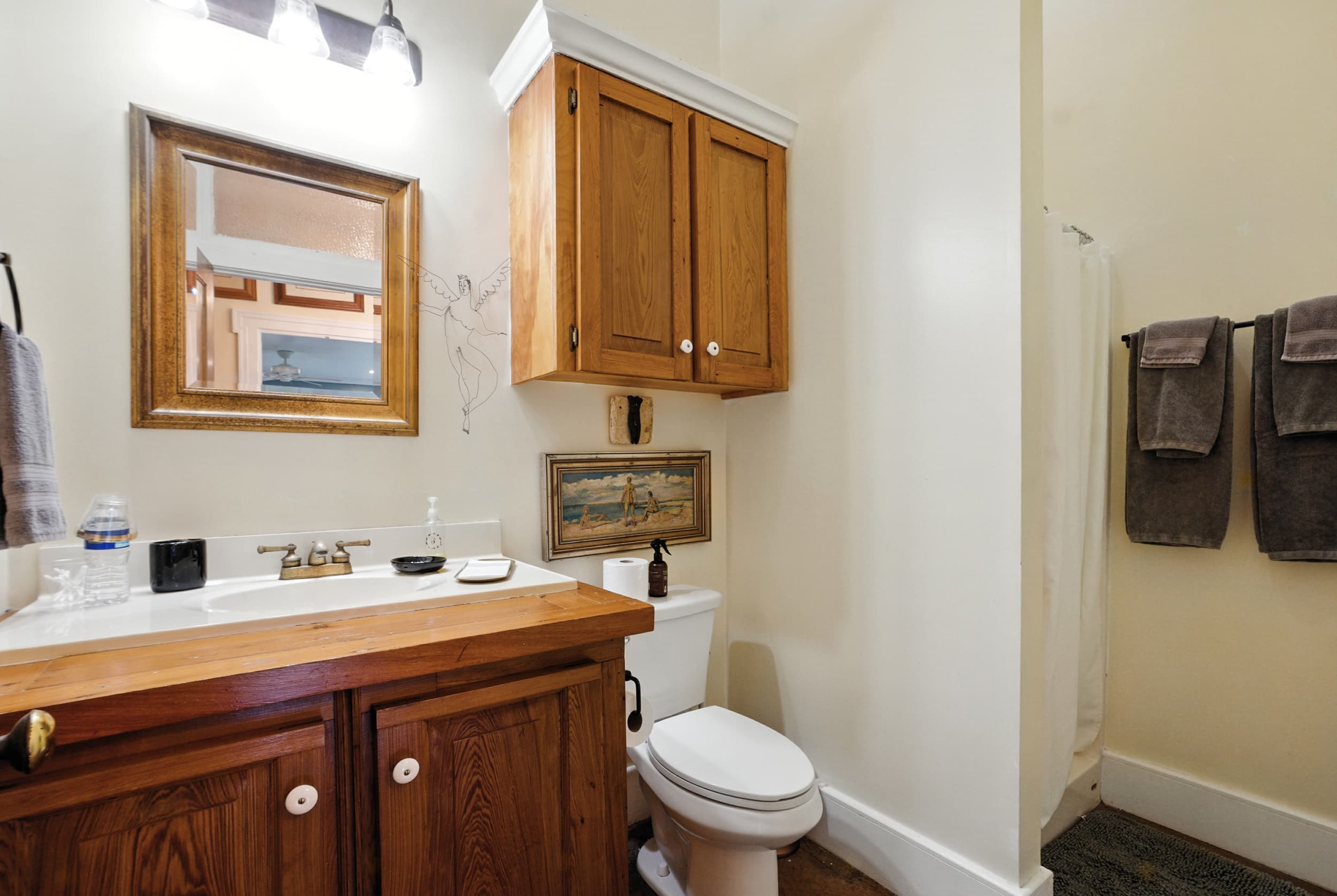 Cozy bathroom featuring a rustic wooden vanity and wall cabinet, a wood-framed mirror, and a separate shower area.