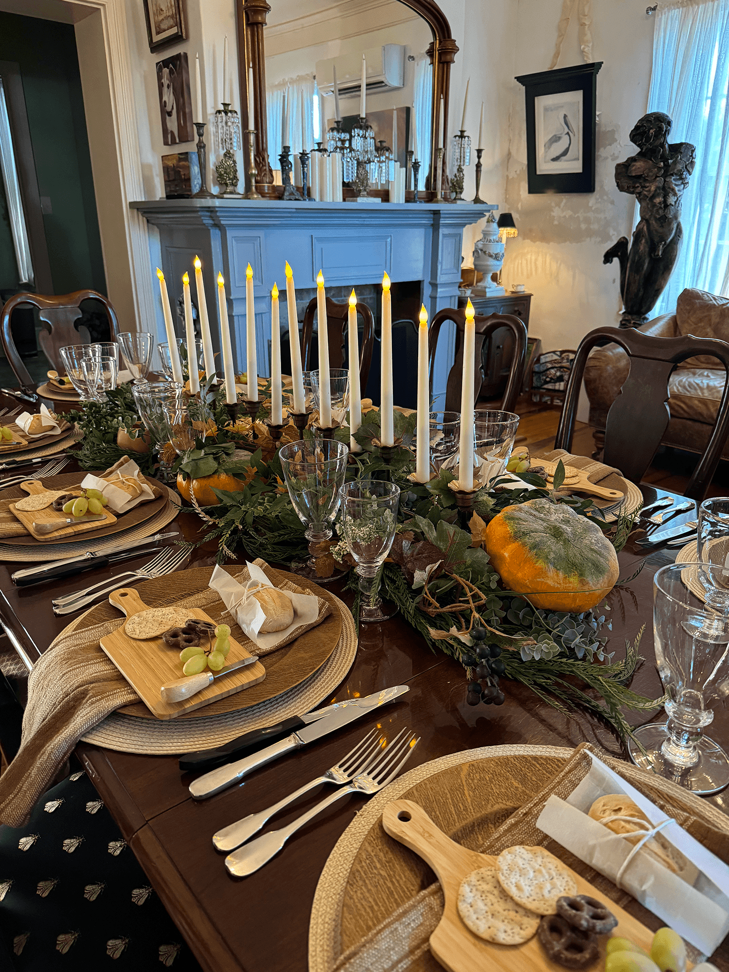 An elegantly set dining table adorned with greenery, candles, and seasonal decorations.