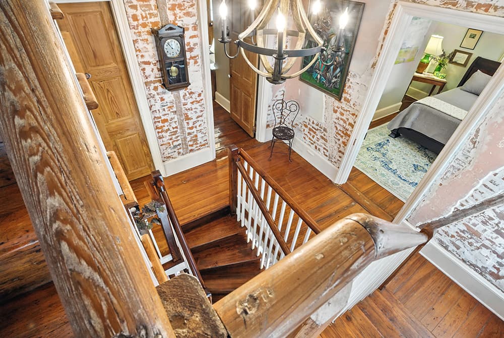 A view of a staircase from above, featuring wooden steps, a vintage clock, and a doorway leading to a cozy bedroom.
