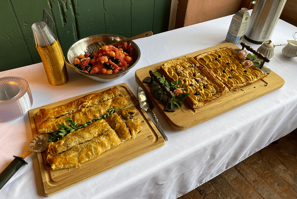Two platters of baked pastries and a bowl of mixed fruit on a table.